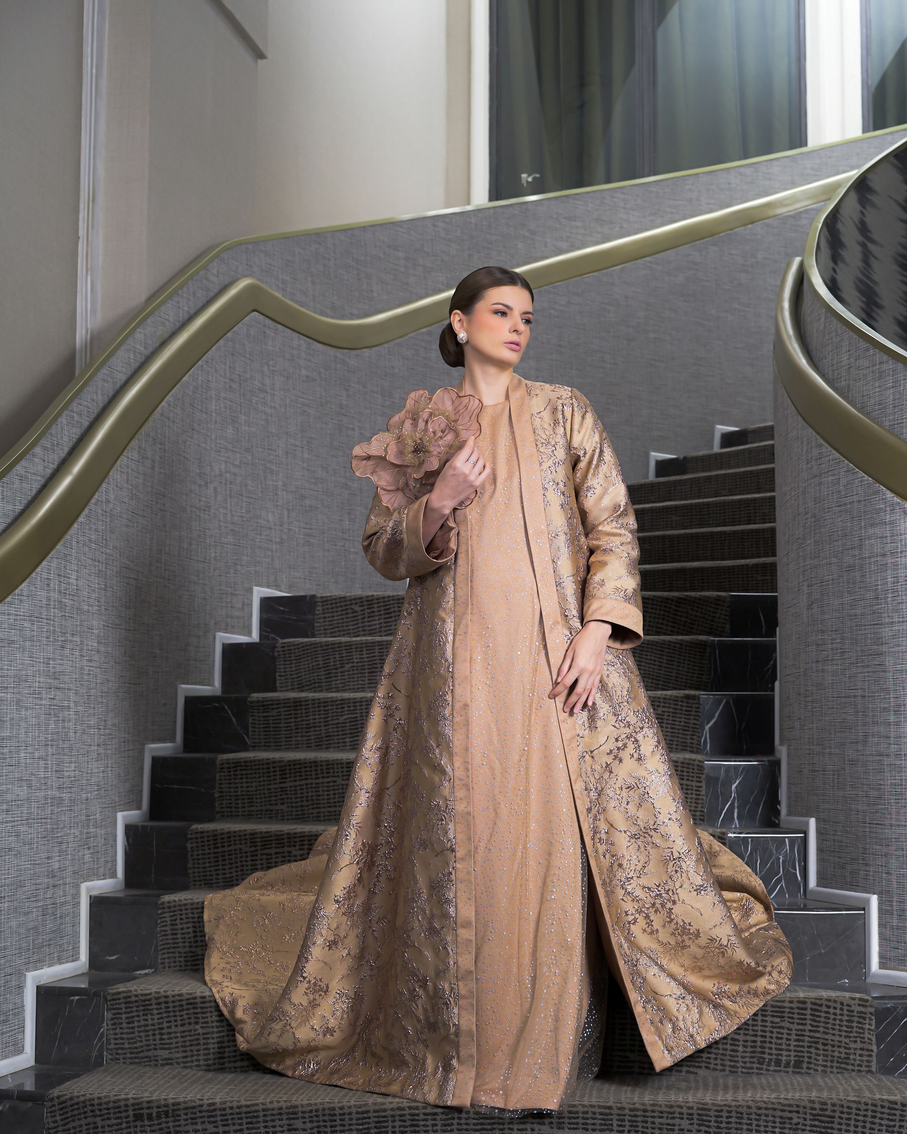 Femme en robe de soirée dorée sur un escalier de palace